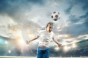 Young boy with soccer ball doing flying kick at stadium