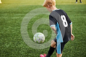 Young boy with soccer ball is in motion on green grass background