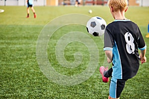 Young boy with soccer ball is in motion on green grass background