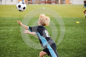 Young boy with soccer ball is in motion on green grass background