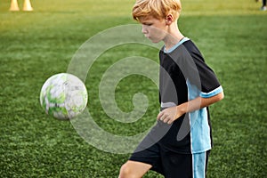 Young boy with soccer ball is in motion on green grass background