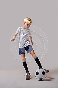 young boy soccer player playing with ball, kicking