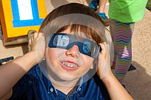 Young Boy With Solar Eclipse Glasses Looks Up at the Sky as the photo