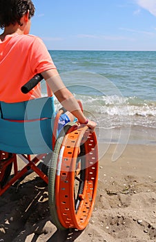 Young boy on the special wheelchair with wheels to move on the s