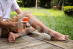 Young boy spraying insect repellents on his leg with spray bott