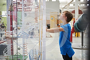 Young boy standing looking at a science exhibit, side view photo