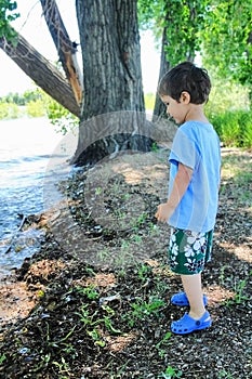 Young boy standing on the shore of a lake
