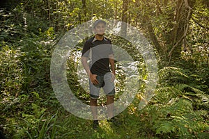 Young boy standing smiling and wearing shorts in the middle of the forest exploring the nature at a youth camp