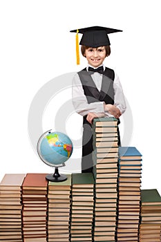 Young boy is standing at stacks of books