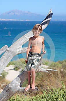 Mladý chlapec stojace v strom na slnečný pláž 