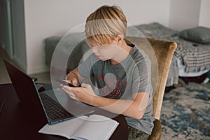 young boy studies using computer and smartphone