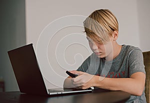 young boy studies using computer and smartphone