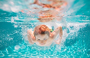 Young boy swim and dive underwater. Under water portrait in swim pool. Child boy diving into a swimming pool.