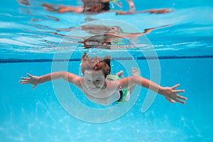 Young boy swim and dive underwater. Under water portrait in swim pool. Child boy diving into a swimming pool. Beach sea