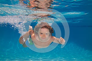 Young boy swim and dive underwater. Under water portrait in swim pool. Child boy diving into a swimming pool. Cute boy