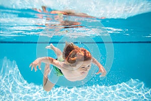Young boy swim and dive underwater. Under water portrait in swim pool. Child boy diving into a swimming pool. Summer