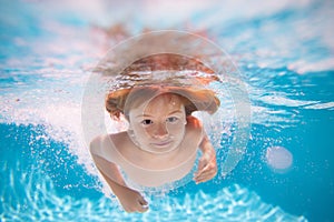 Young boy swim and dive underwater. Under water portrait in swim pool. Child boy diving into a swimming pool. Water play