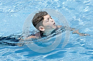 Young boy swimming and having fun in swimming-pool