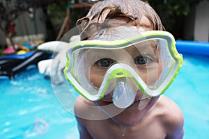 Young boy in swimming mask in backyard pool