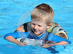 Young boy in the swimming pool with a rubber ring.