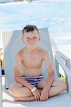 Young boy in a swimsuit on a shelf by the pool