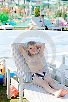 Young boy in a swimsuit on a shelf by the pool