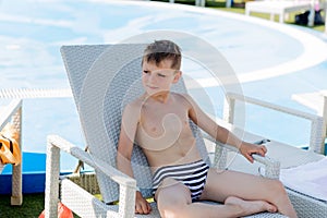 Young boy in a swimsuit on a shelf by the pool