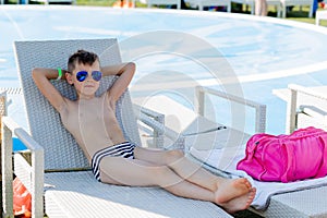 Young boy in a swimsuit on a shelf by the pool