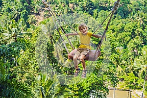 Young boy swinging in the jungle rainforest of Bali island, Indonesia. Swing in the tropics. Swings - trend of Bali