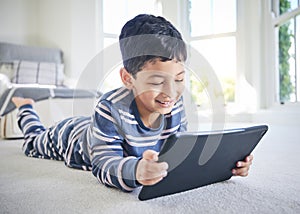 Young boy, tablet and games or cartoon streaming online with internet, e learning and relax on carpet in house. Watch