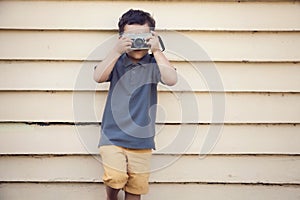 Young boy taking photo with camera, sunshine, outdoors