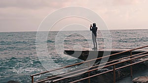 Young boy taking video of rainy sea. Attractive man making photo at promenade. Lonely boy making pictures of stormy sea. Melanchol