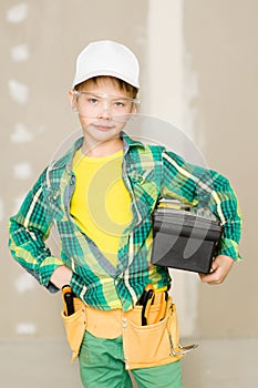 Young boy with tool belt holding toolbox