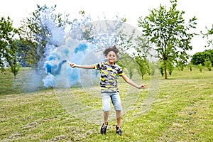 Young boy trailing a blue smoke flare in a park