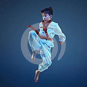 Young boy training karate on blue background