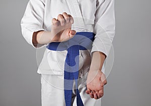 Young boy training karate on gray background. Boy with a kimono
