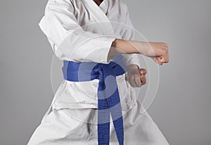Young boy training karate on gray background. Boy with a kimono