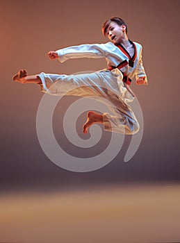 Young boy training karate on blue background