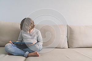 Young boy usina tablet on sofa at home photo