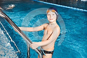 Young boy using ladder to exit swimming pool
