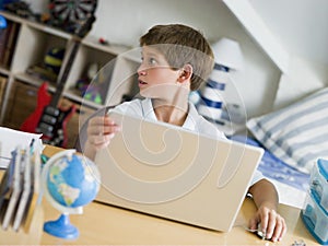 Young Boy Using A Laptop In His Bedroom