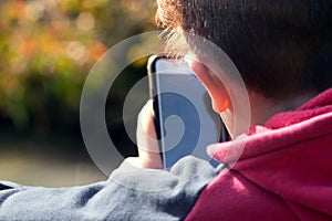 Young boy using phone outdoors