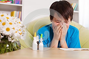 Young boy with various nose sprays sneezing in allergy season photo