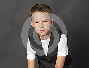 Young boy in vest and tee shirt looking at camera