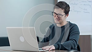 Young boy video conferencing with tutor on laptop in school