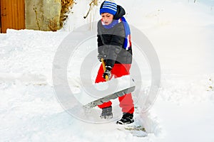 A young boy in the village cleans the snow and makes a walk