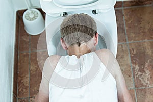 Young boy vomiting into a toilet bowl