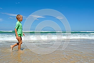 Young boy walking along the waters edge