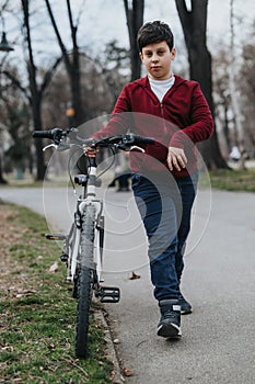 Young boy walking with his bicycle in the park, enjoying an active day outdoors photo