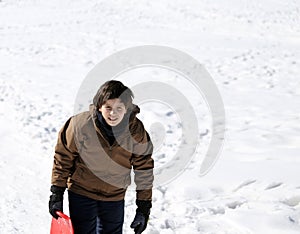 Young boy walks with tobogganing on fresh snow in the winter photo